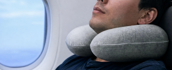 Uomo che riposa in aereo con un cuscino da viaggio, immagine dedicata ai consigli per prevenire e gestire il jet lag