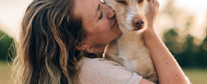 Ragazza che abbraccia e bacia il proprio cane, immagine dedicata alla Giornata Mondiale del Cane e alla cura del suo benessere