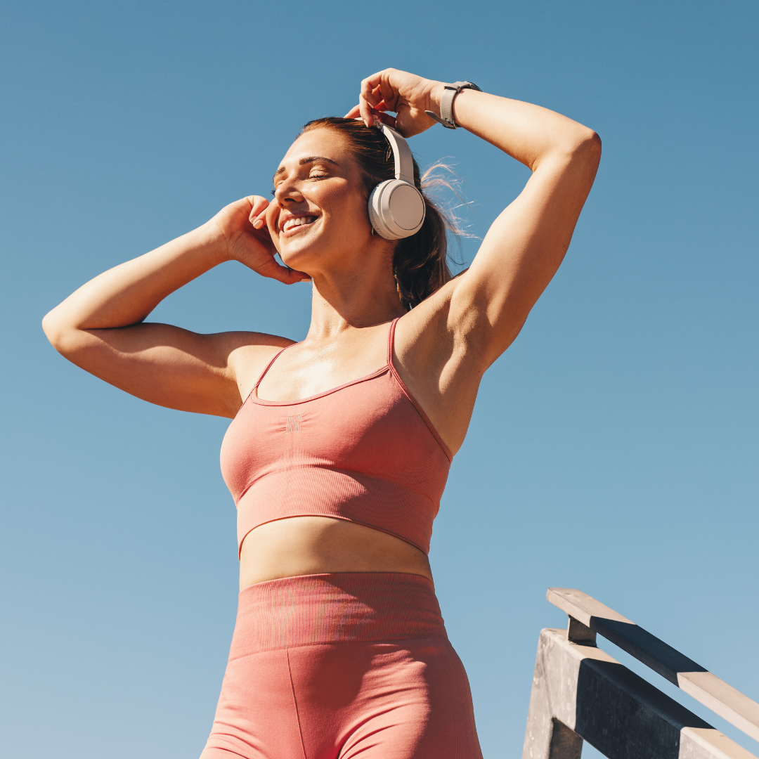 Donna in abbigliamento sportivo con cuffie all’aperto, immagine dedicata allo sport all'aperto con il caldo, all’idratazione e al recupero muscolare