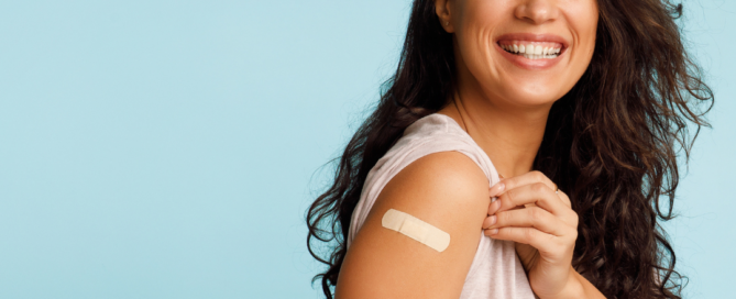 Donna sorridente con un cerotto sul braccio dopo la vaccinazione anti-influenzale, a rappresentare la prevenzione contro l'influenza stagionale.