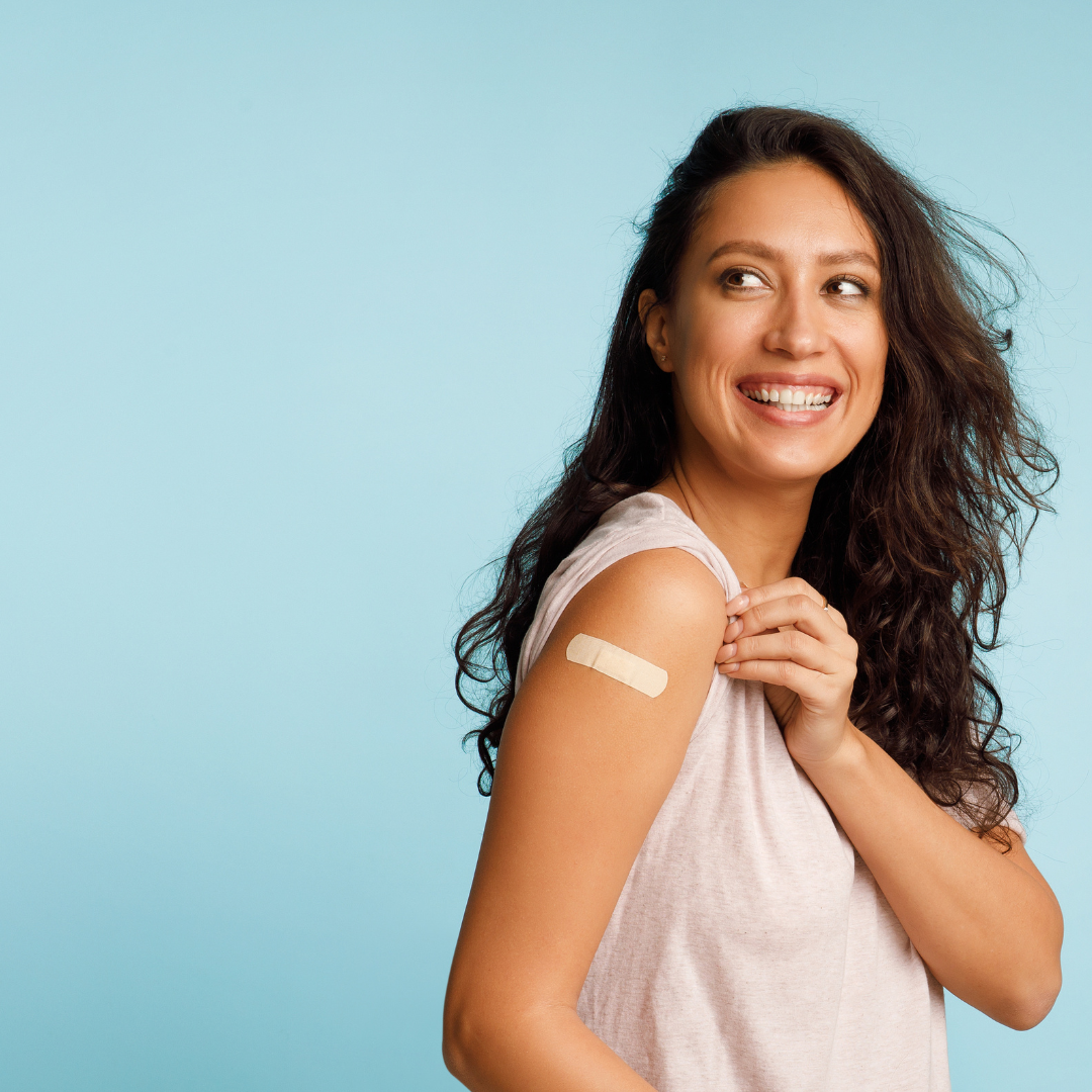 Donna sorridente con un cerotto sul braccio dopo la vaccinazione anti-influenzale, a rappresentare la prevenzione contro l'influenza stagionale.