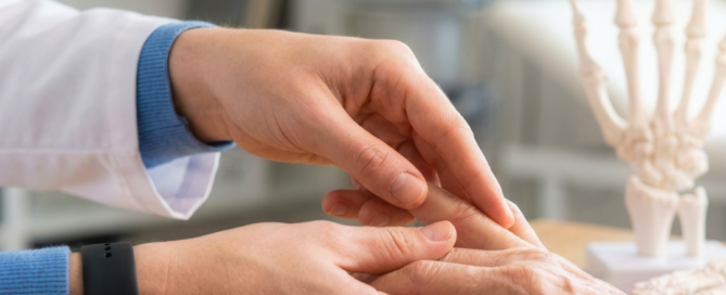 Professionista sanitario che esamina la mano di una persona anziana, con un modello anatomico dello scheletro della mano sullo sfondo, a rappresentare la prevenzione dell'osteoporosi e la salute delle ossa.